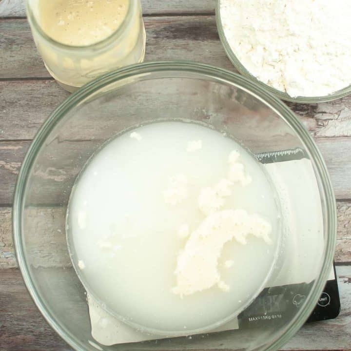 A glass bowl filled with ingredients for a dutch oven sourdough bread recipe.