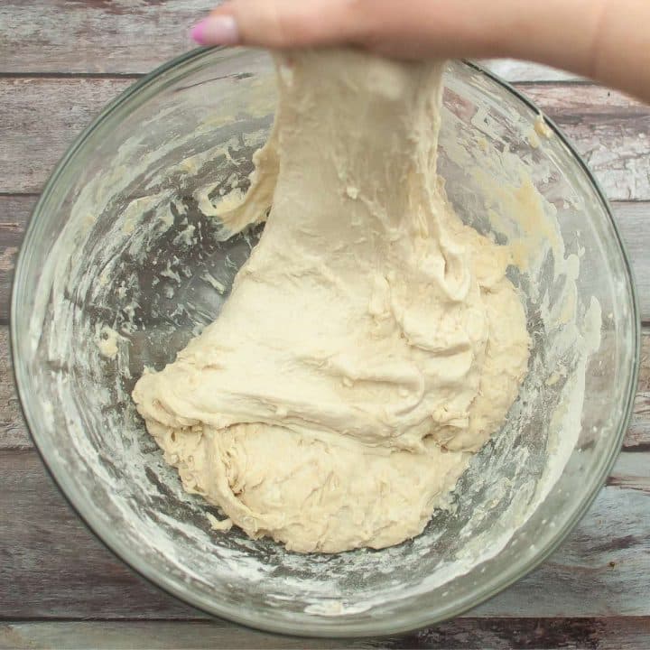 A person kneading sourdough in a bowl.