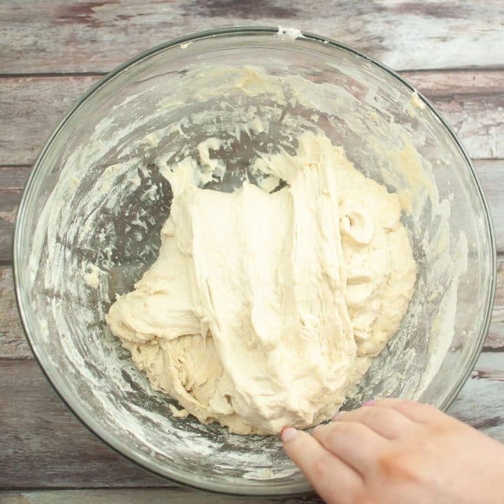 A person mixing  sourdough in a bowl.
