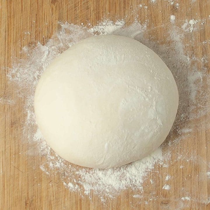A dough ball for a sourdough dutch oven bread loaf is sitting on top of flour.