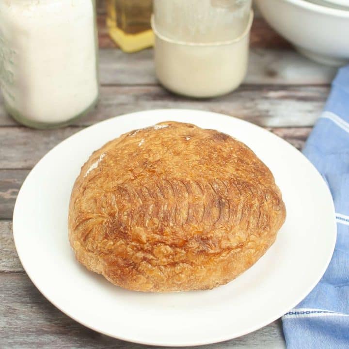 A loaf of sourdough bread on a plate next to a jar of milk.