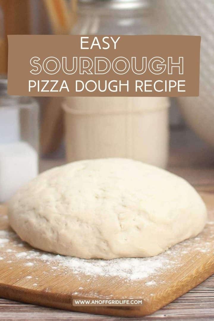 Ball of sourdough pizza dough on a floured wooden board, with a text overlay: "Easy Sourdough Pizza Dough Recipe.
