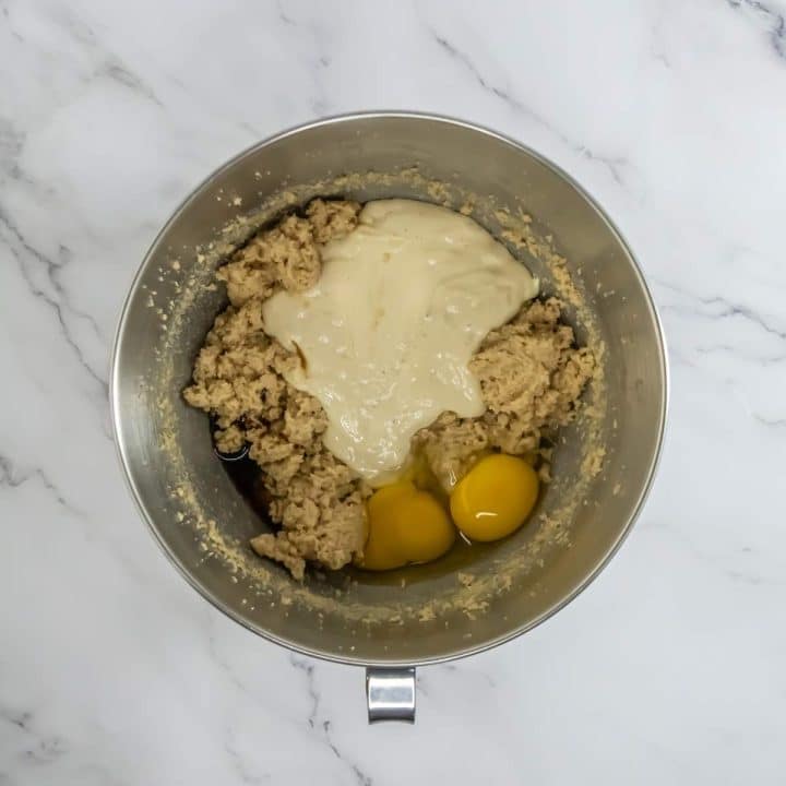 A metal bowl with eggs, flour, and butter in it.