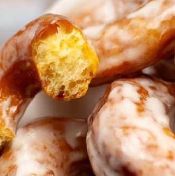 Close-up of glazed donuts with a bite taken out of one, showcasing the delightful texture of a perfected sourdough donut recipe.