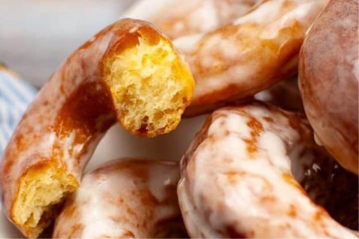 Close-up of glazed donuts with a bite taken out of one, showcasing the delightful texture of a perfected sourdough donut recipe.