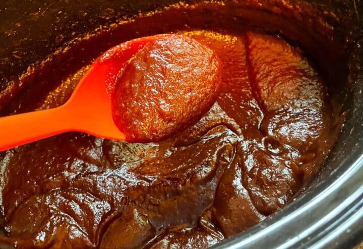 A spoonful of sauce in a crock pot.