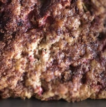 Close-up of a baked strawberry rhubarb dessert with a crumbly texture and visible berries.