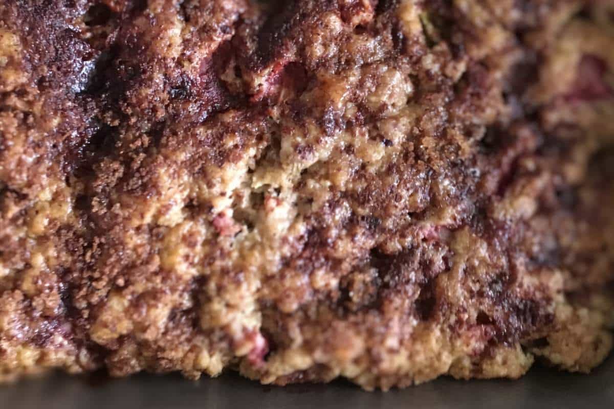 Close-up of a baked strawberry rhubarb dessert with a crumbly texture and visible berries.