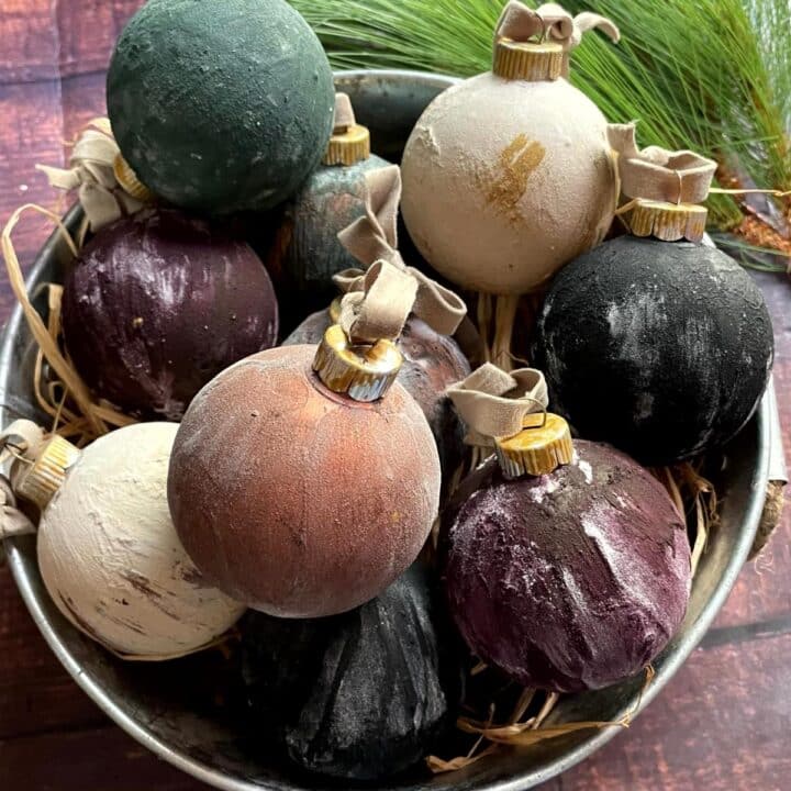 Vintage Christmas ornaments in a metal bowl with pine cones.