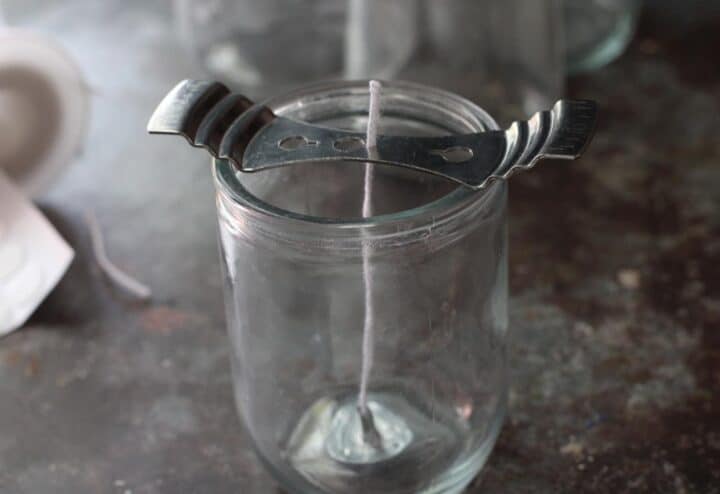 A glass jar with a spoon and a straw in it.