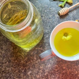 A jar of honey and dandelion tea next to a spoon.