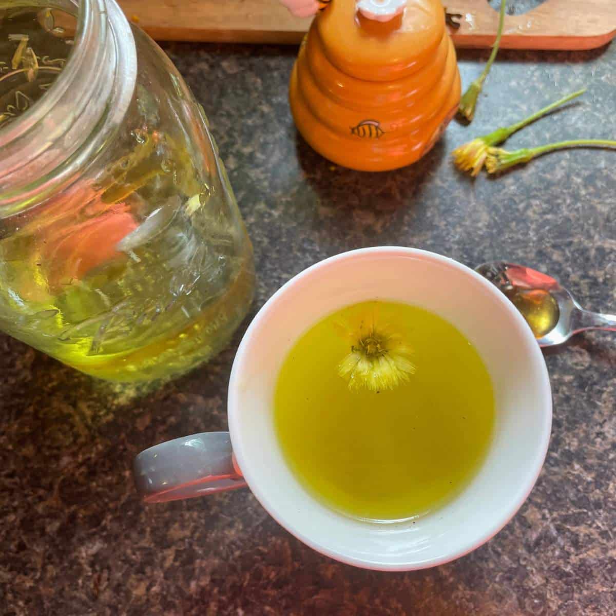 Dandelion tea in a jar next to a spoon.