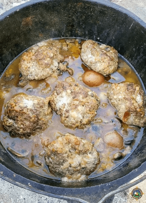 salisbury steak cooked in dutch oven over a campfire