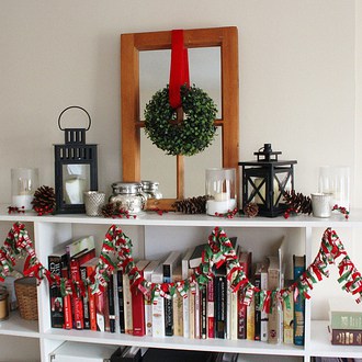 A white bookcase with Christmas decorations and books on it, showcasing pioneer craft ideas for kids.