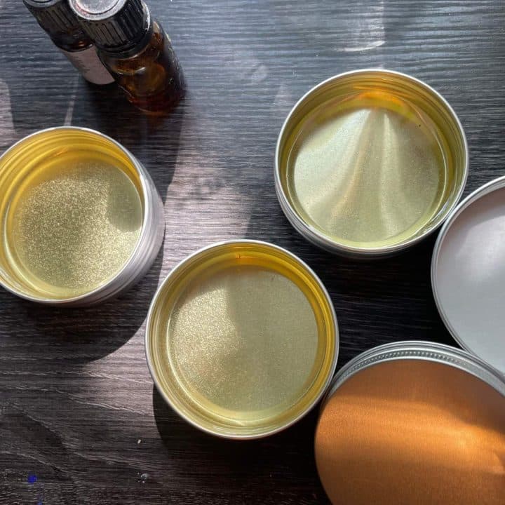 Three tins of beeswax salve recipe on a table.