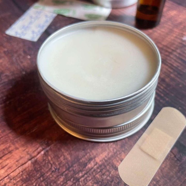 A tin of beeswax and a bandage on a wooden table.
