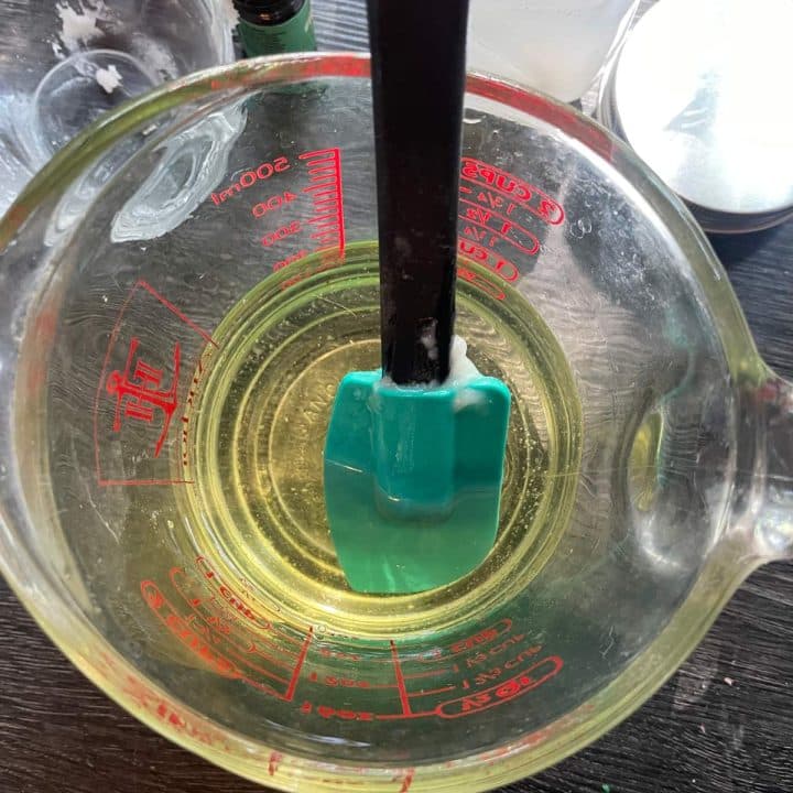 A measuring cup filled with green liquid and a green spatula.
