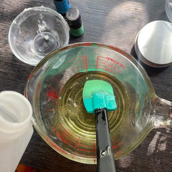 A measuring cup filled with liquid and a green brush.