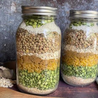 Two mason jars filled with pasta and peas.