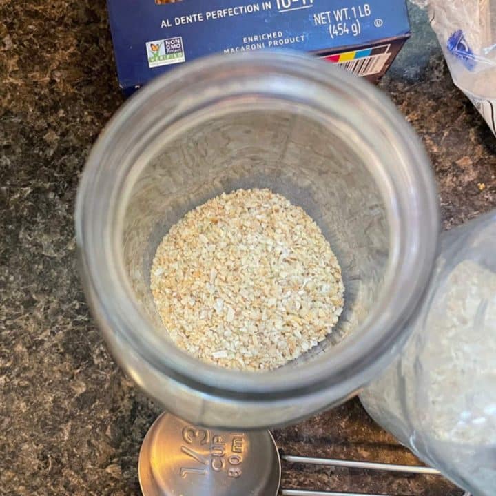 Ditalini pasta for soup in a jar next to a measuring cup.