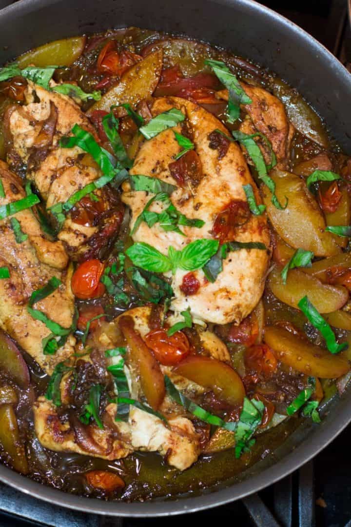 A Dutch oven full of chicken breast and vegetables on a stove.