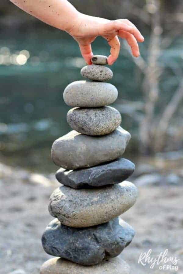 child's hand stacking rocks