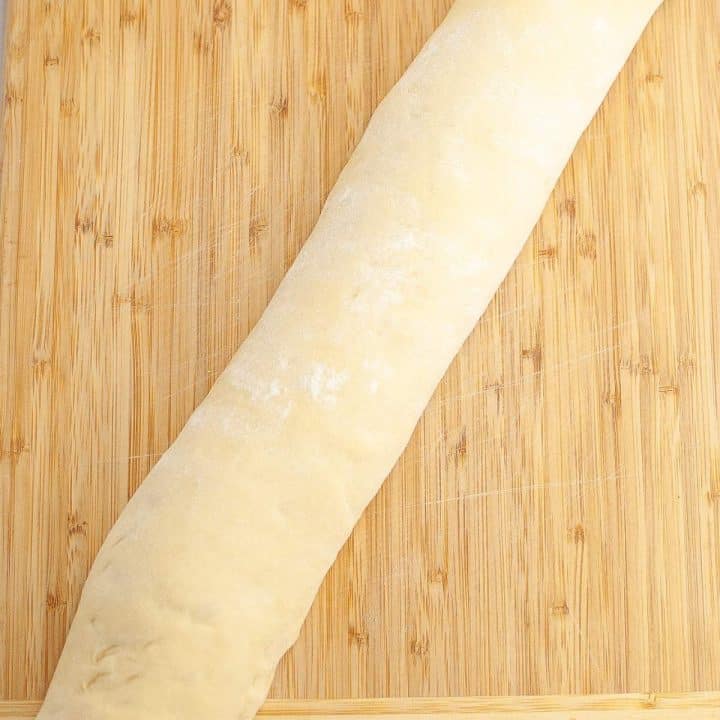 A rolled-out piece of dough on a wooden surface.