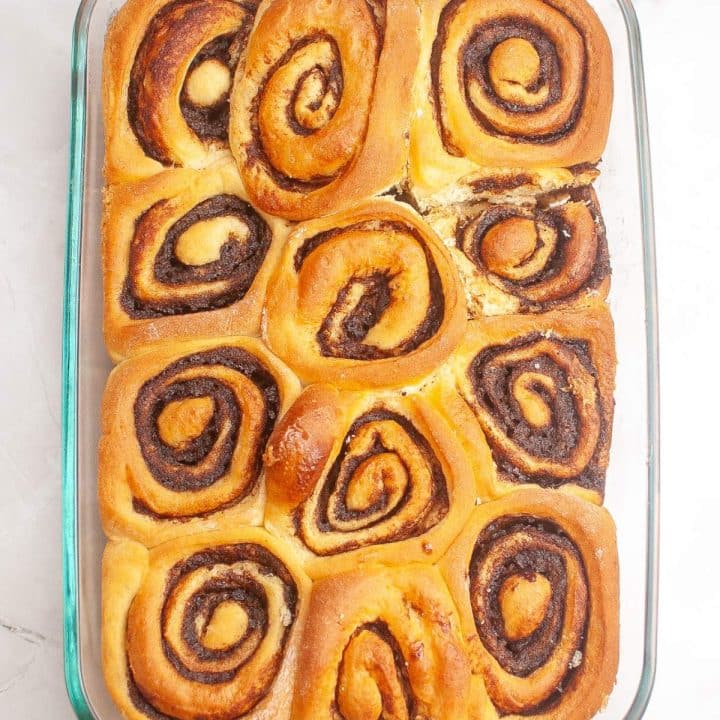 A glass baking dish containing freshly baked cinnamon rolls.