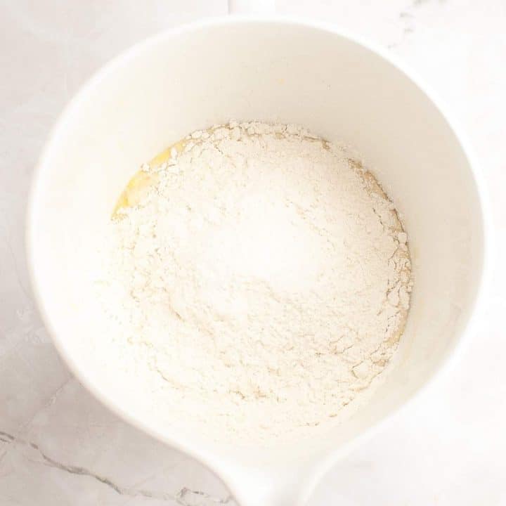 Flour in a white mixing bowl on a countertop.