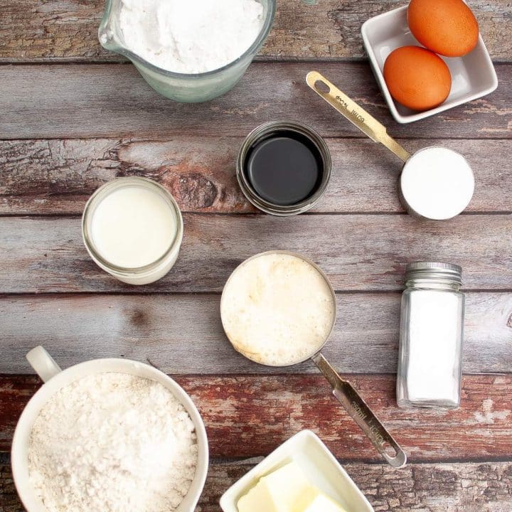Various baking ingredients for sourdough donut recipe arranged on a wooden surface.