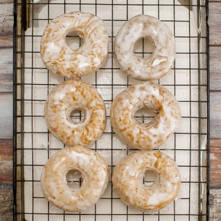 Glazed sourdough doughnuts on a cooling rack.
