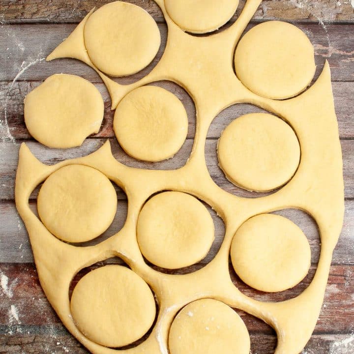 Sourdough donut dough with round cut-outs on a wooden surface.