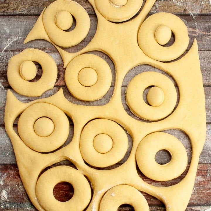 Dough with circular cutouts on a wooden surface.