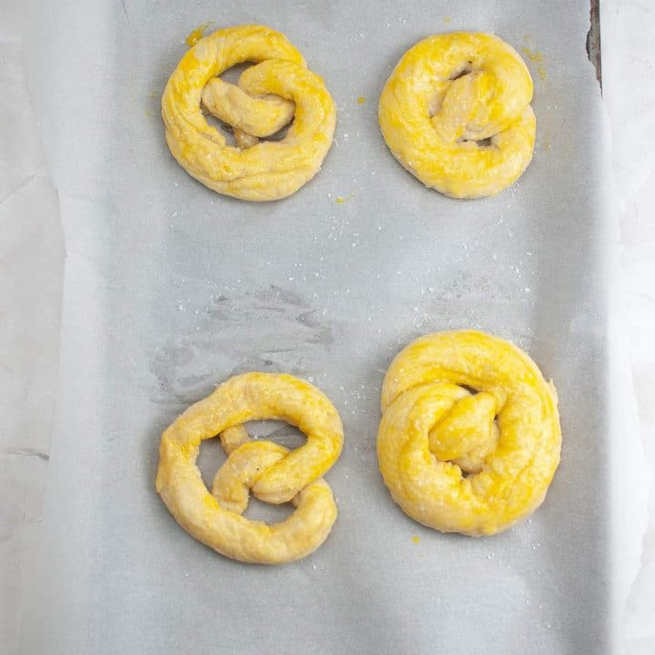 Unbaked pretzels on parchment paper ready for the oven.