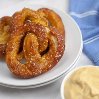 A plate of salted sourdough pretzels served with mustard dipping sauce.