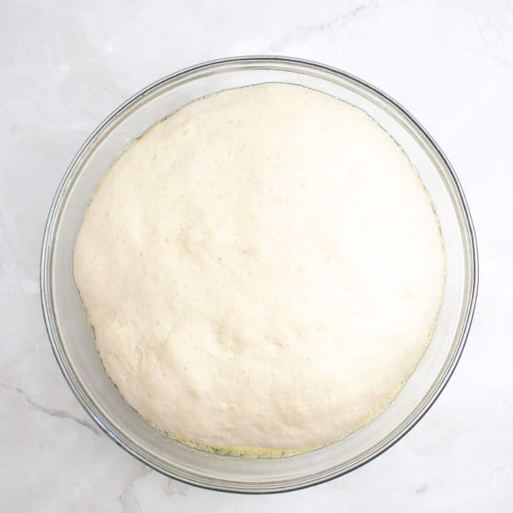 Bread dough after rising in a glass bowl.