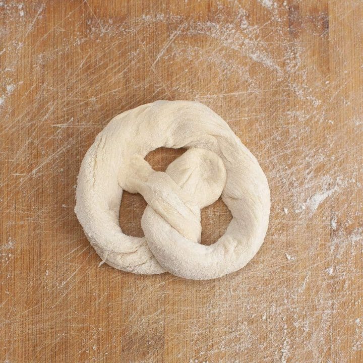 Unbaked pretzel dough on a floured wooden surface.
