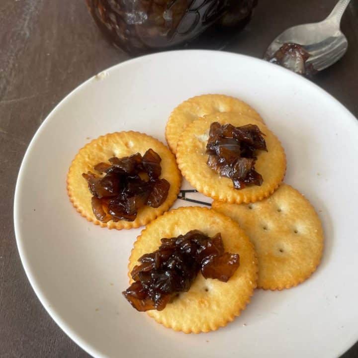 A plate with crackers and a jar of sweet balsamic onion relish.