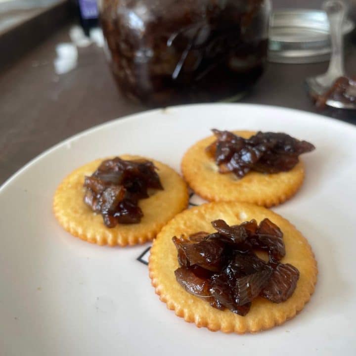 A plate with crackers and a jar of sweet balsamic onion relish.