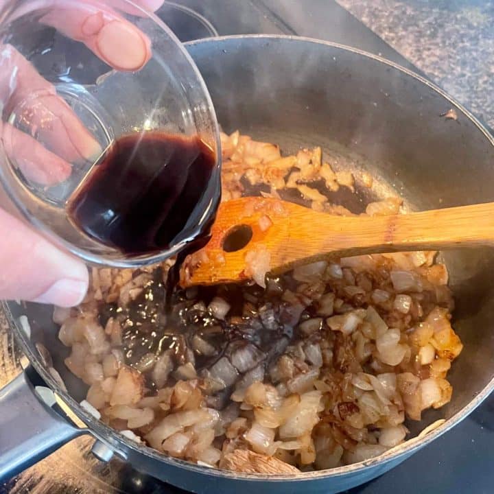 A person pouring a sauce into a pan.