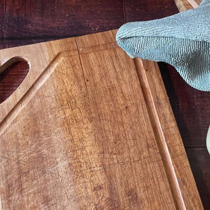 A wooden cutting board with a green cloth on it.