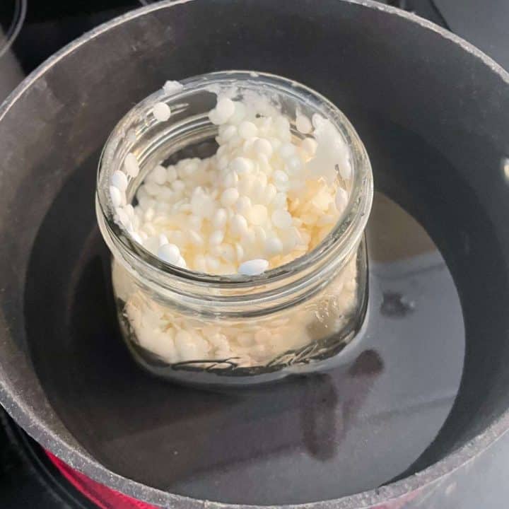 A jar of beeswax pellets in a pot on the stove.